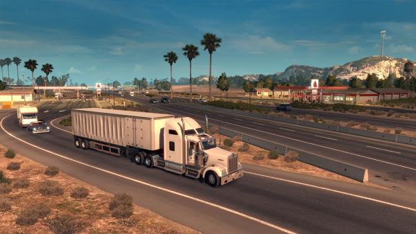 Screenshot: Ein Truck fährt in einer karg bewachsenen Landschaft auf eine Autobahn auf.