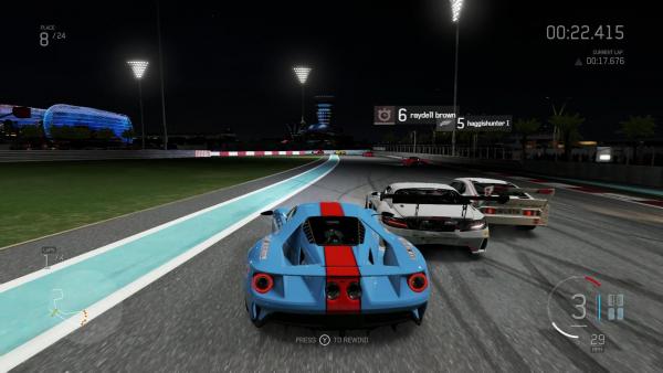 Screenshot: Ein gestreifter Sportwagen fährt bei Nacht beinahe auf gleicher Höhe mit zwei Gegnern auf eine Kurve zu