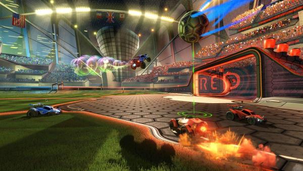 Screenshot: Der Ball wirbeld durch die Luft, während vier Autos vor vollbesetzten Tribünen um seine Aufnahme fahren